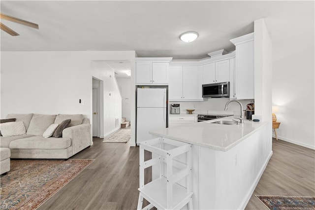 kitchen featuring ceiling fan, sink, hardwood / wood-style floors, white fridge, and white cabinets