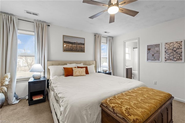 bedroom featuring ensuite bathroom, ceiling fan, and light carpet