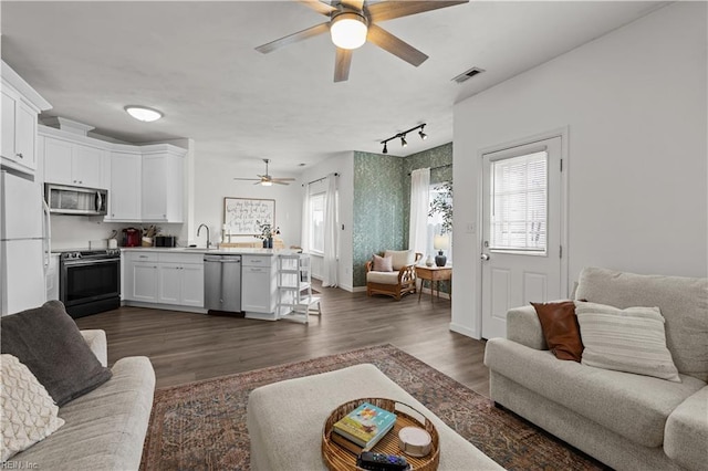 living room featuring dark hardwood / wood-style flooring, rail lighting, a wealth of natural light, and ceiling fan