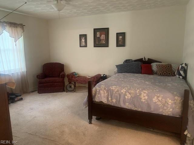 carpeted bedroom featuring ceiling fan and a textured ceiling