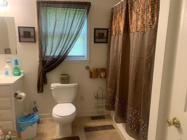 bathroom with curtained shower, vanity, and toilet