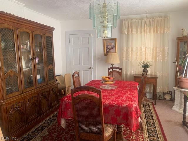 carpeted dining room with a notable chandelier and a textured ceiling