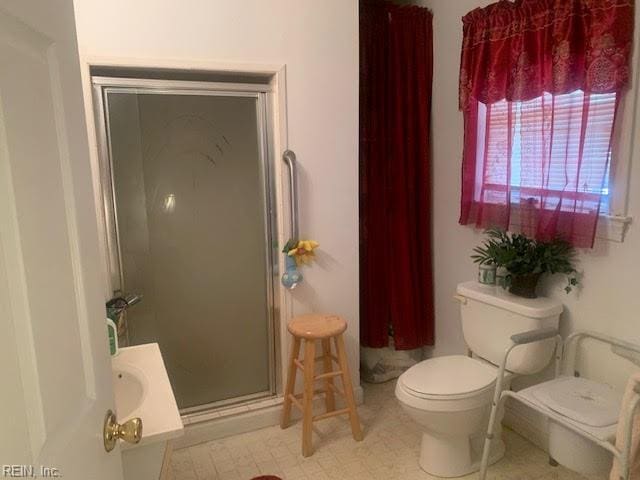 bathroom featuring toilet and a shower with door