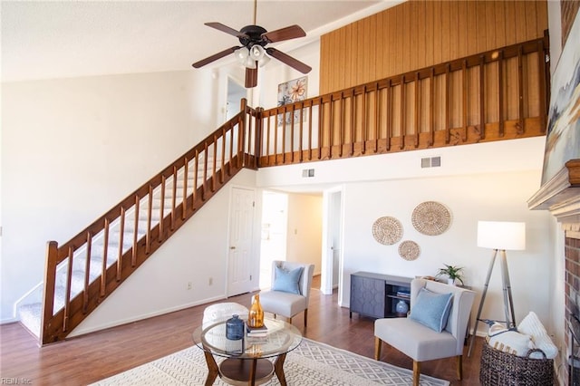 living room featuring ceiling fan, a fireplace, high vaulted ceiling, and dark wood-type flooring