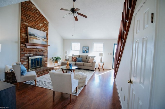 living room with a brick fireplace, ceiling fan, vaulted ceiling, and hardwood / wood-style flooring