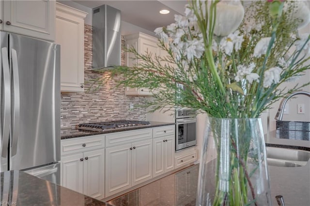 kitchen with wall chimney exhaust hood, white cabinetry, and stainless steel appliances