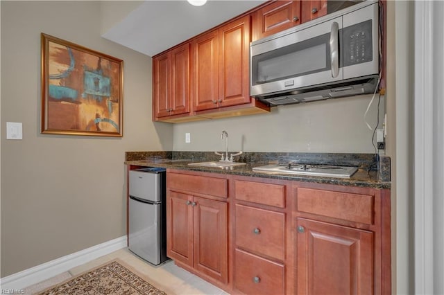 kitchen featuring stainless steel appliances, dark stone countertops, and sink