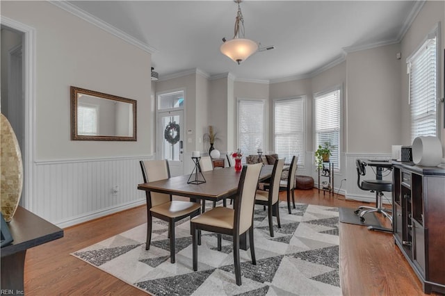 dining area with plenty of natural light, ornamental molding, and light hardwood / wood-style flooring