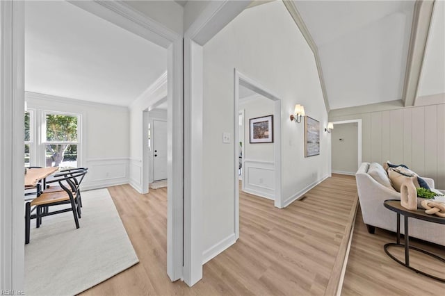 hallway with light hardwood / wood-style floors, crown molding, and vaulted ceiling