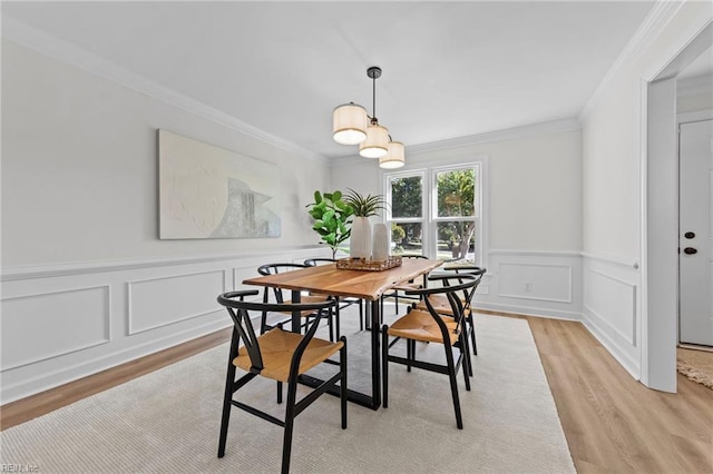 dining space with ornamental molding and light hardwood / wood-style flooring