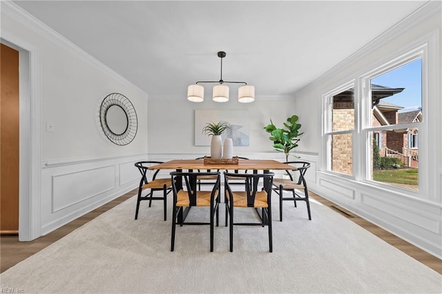 dining area featuring wood-type flooring and crown molding