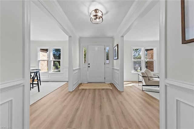 foyer featuring crown molding, a wealth of natural light, and light hardwood / wood-style flooring