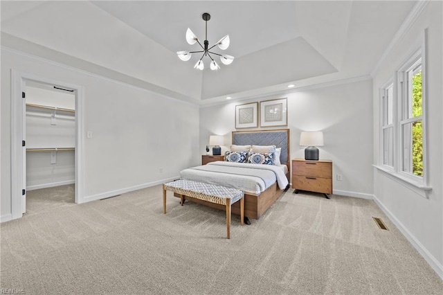 bedroom with an inviting chandelier, a raised ceiling, a spacious closet, light colored carpet, and a closet