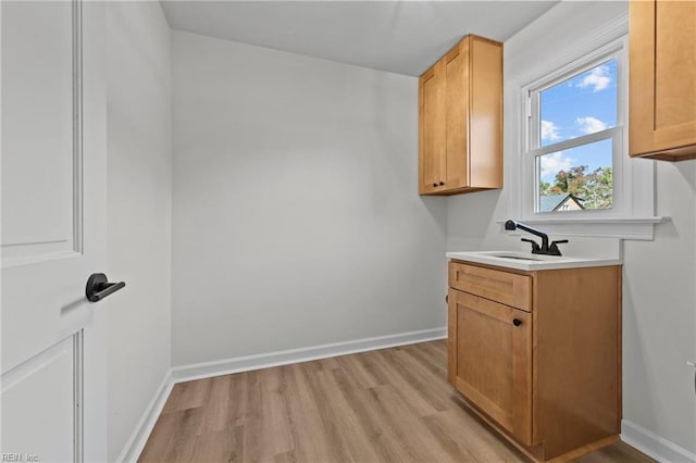 clothes washing area featuring sink and light hardwood / wood-style floors