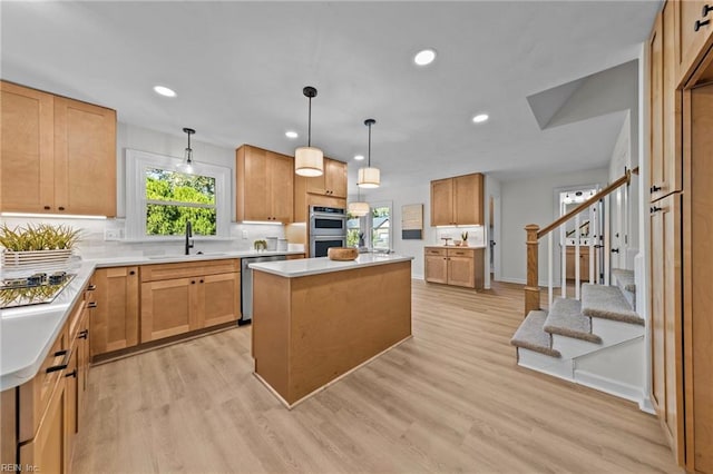 kitchen with decorative light fixtures, a kitchen island, stainless steel appliances, and light hardwood / wood-style flooring