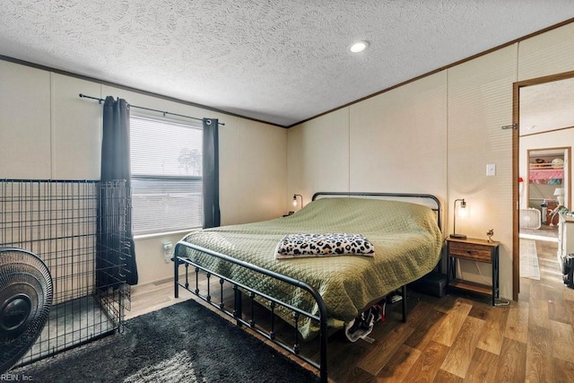 bedroom featuring hardwood / wood-style floors, a textured ceiling, and crown molding