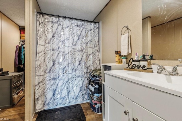 bathroom featuring vanity, wood-type flooring, a textured ceiling, and ornamental molding