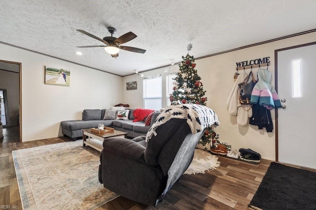 living room featuring wood-type flooring, a textured ceiling, ceiling fan, and ornamental molding