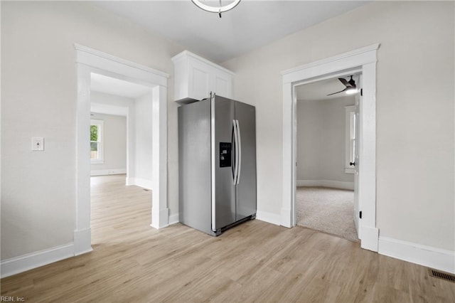 kitchen with white cabinetry, stainless steel fridge, ceiling fan, and light wood-type flooring