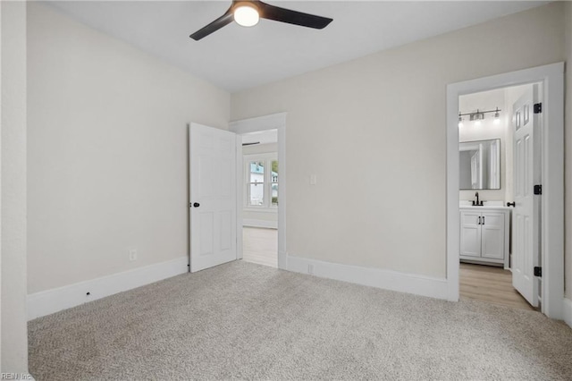 unfurnished bedroom featuring ceiling fan, sink, light carpet, and connected bathroom