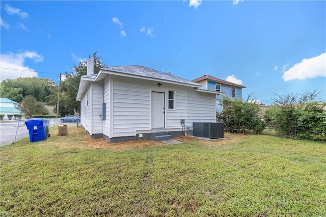 rear view of house with central air condition unit and a yard