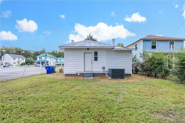 rear view of house with a lawn and central AC