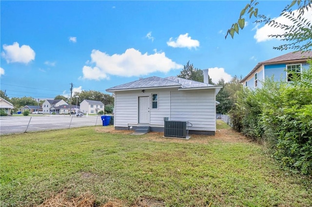 rear view of house featuring central AC and a yard