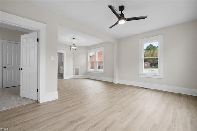 unfurnished living room featuring ceiling fan with notable chandelier and light hardwood / wood-style floors