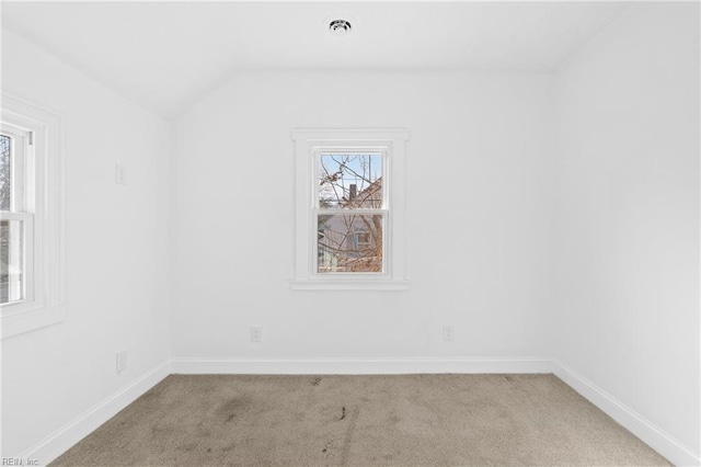 carpeted spare room featuring vaulted ceiling