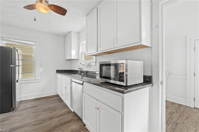 kitchen with appliances with stainless steel finishes, ceiling fan, sink, hardwood / wood-style floors, and white cabinetry