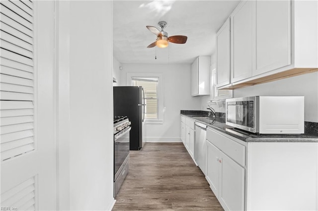 kitchen with dark hardwood / wood-style flooring, stainless steel appliances, ceiling fan, sink, and white cabinetry