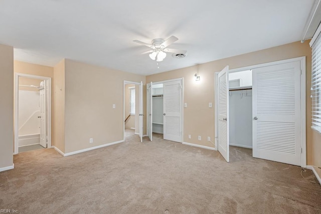 unfurnished bedroom with ensuite bath, ceiling fan, light colored carpet, and multiple closets