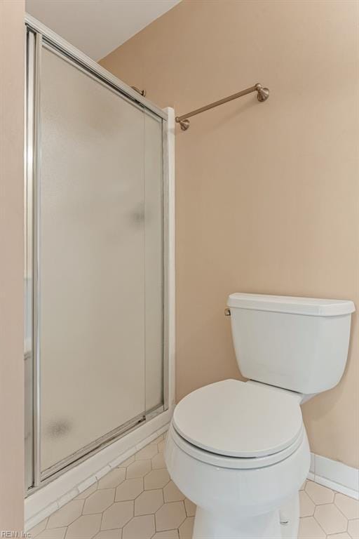 bathroom featuring tile patterned floors, toilet, and a shower with shower door