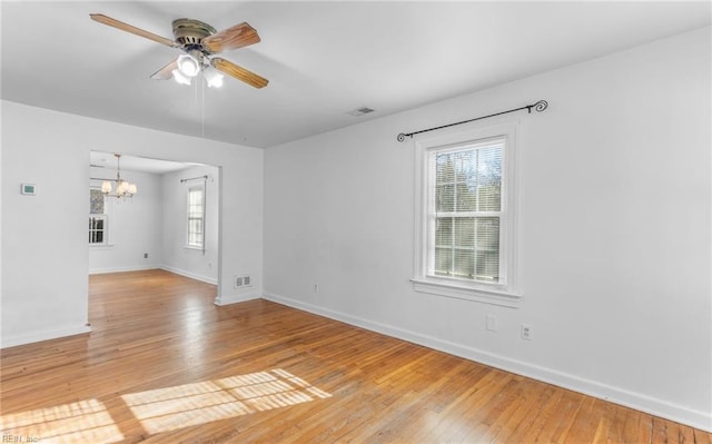 spare room with light hardwood / wood-style flooring, a healthy amount of sunlight, and ceiling fan with notable chandelier