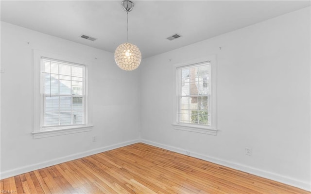 spare room with a wealth of natural light and hardwood / wood-style floors