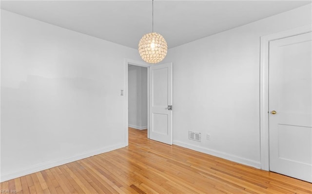 unfurnished room featuring light hardwood / wood-style flooring and an inviting chandelier