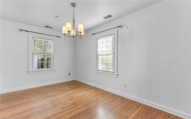 spare room featuring hardwood / wood-style floors and a chandelier