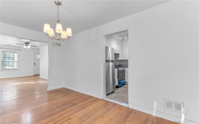 empty room with light hardwood / wood-style flooring and ceiling fan with notable chandelier