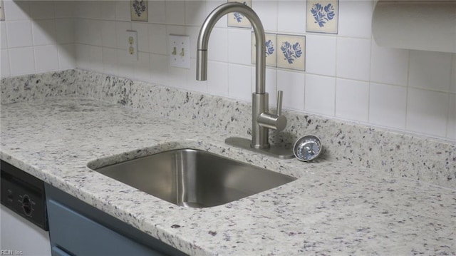 interior details with white dishwasher, light stone countertops, and sink