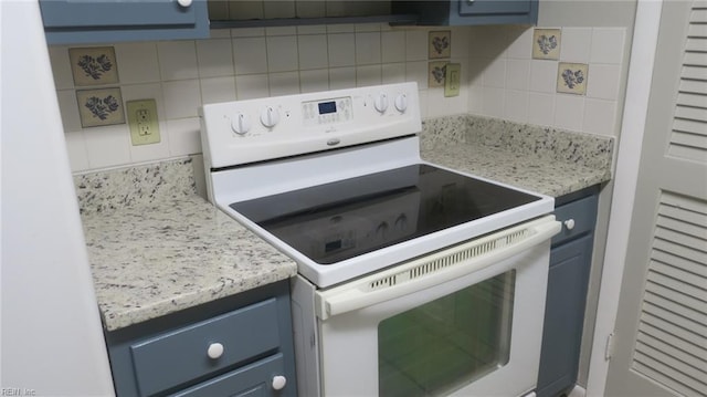 kitchen with decorative backsplash, white range with electric stovetop, blue cabinets, and light stone counters