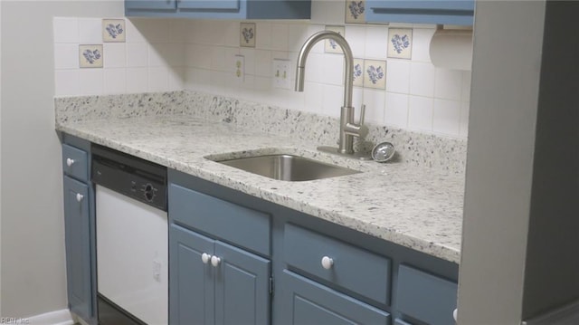 kitchen with tasteful backsplash, light stone counters, blue cabinets, sink, and dishwasher