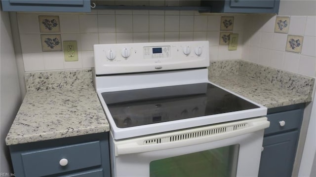 kitchen with white range with electric stovetop, blue cabinetry, and tasteful backsplash