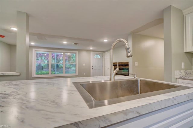 1013 Dare Rd, Yorktown, VA 23692 - kitchen featuring a sink, light stone countertops, recessed lighting, white cabinets, and a glass covered fireplace