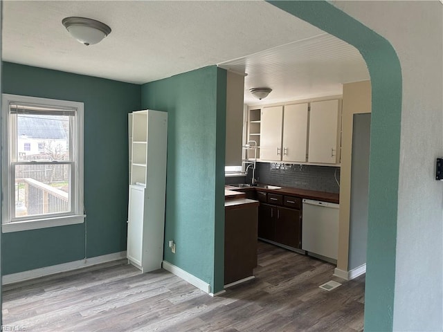 kitchen featuring tasteful backsplash, sink, dishwasher, light hardwood / wood-style floors, and white cabinetry