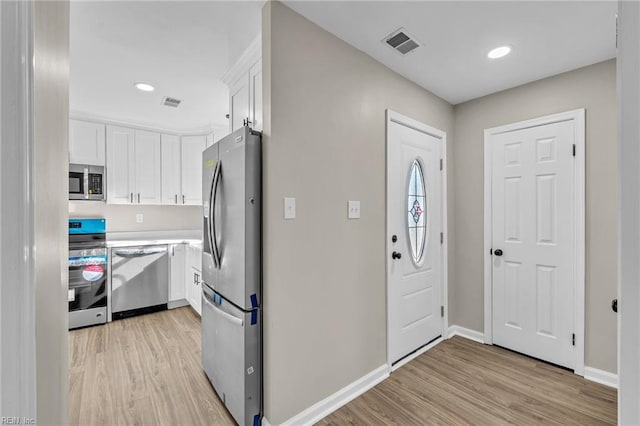 kitchen featuring stainless steel appliances, white cabinetry, and light hardwood / wood-style floors