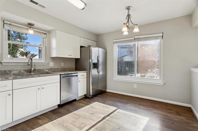 kitchen with sink, a notable chandelier, pendant lighting, white cabinets, and appliances with stainless steel finishes