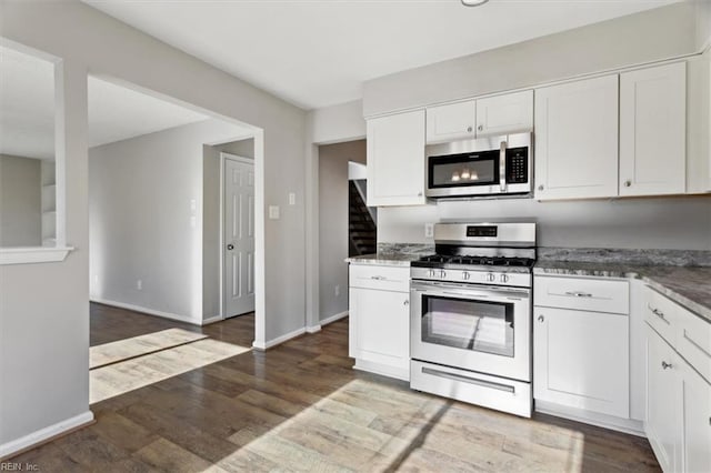 kitchen with white cabinets, dark stone countertops, hardwood / wood-style floors, and appliances with stainless steel finishes