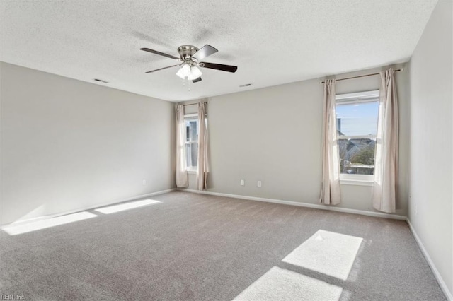 spare room featuring ceiling fan, light colored carpet, and a textured ceiling