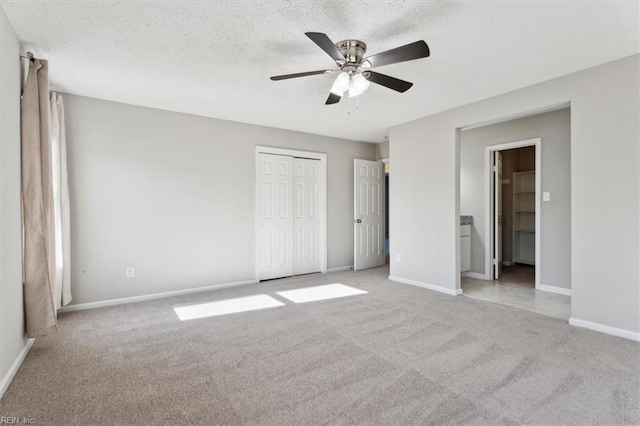 unfurnished bedroom with light carpet, a textured ceiling, a closet, and ceiling fan