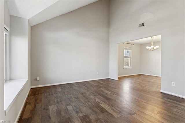 unfurnished room with a textured ceiling, vaulted ceiling, dark wood-type flooring, and a chandelier